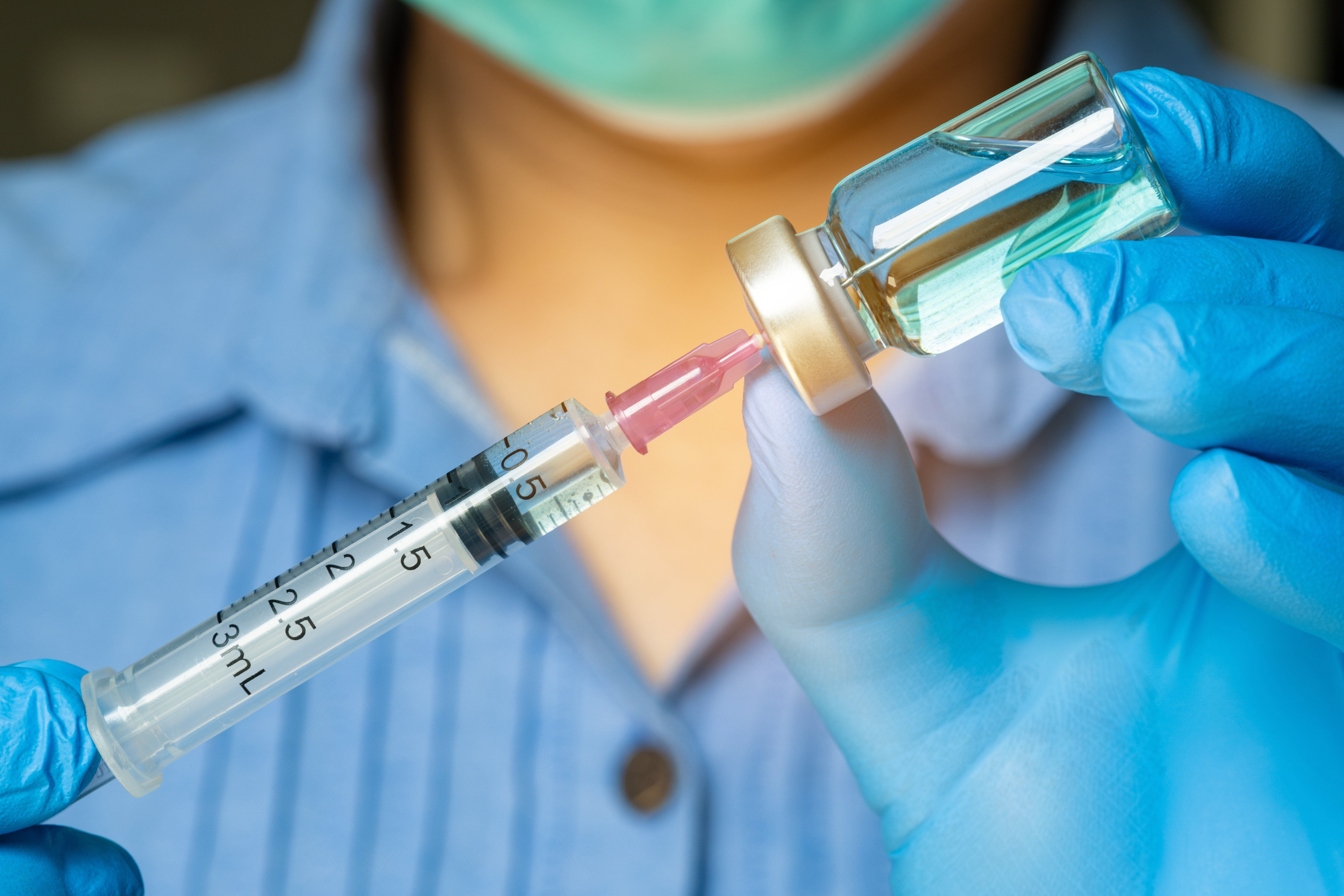 Doctor's,Hand,Holds,A,Syringe,And,A,Blue,Vaccine,Bottle