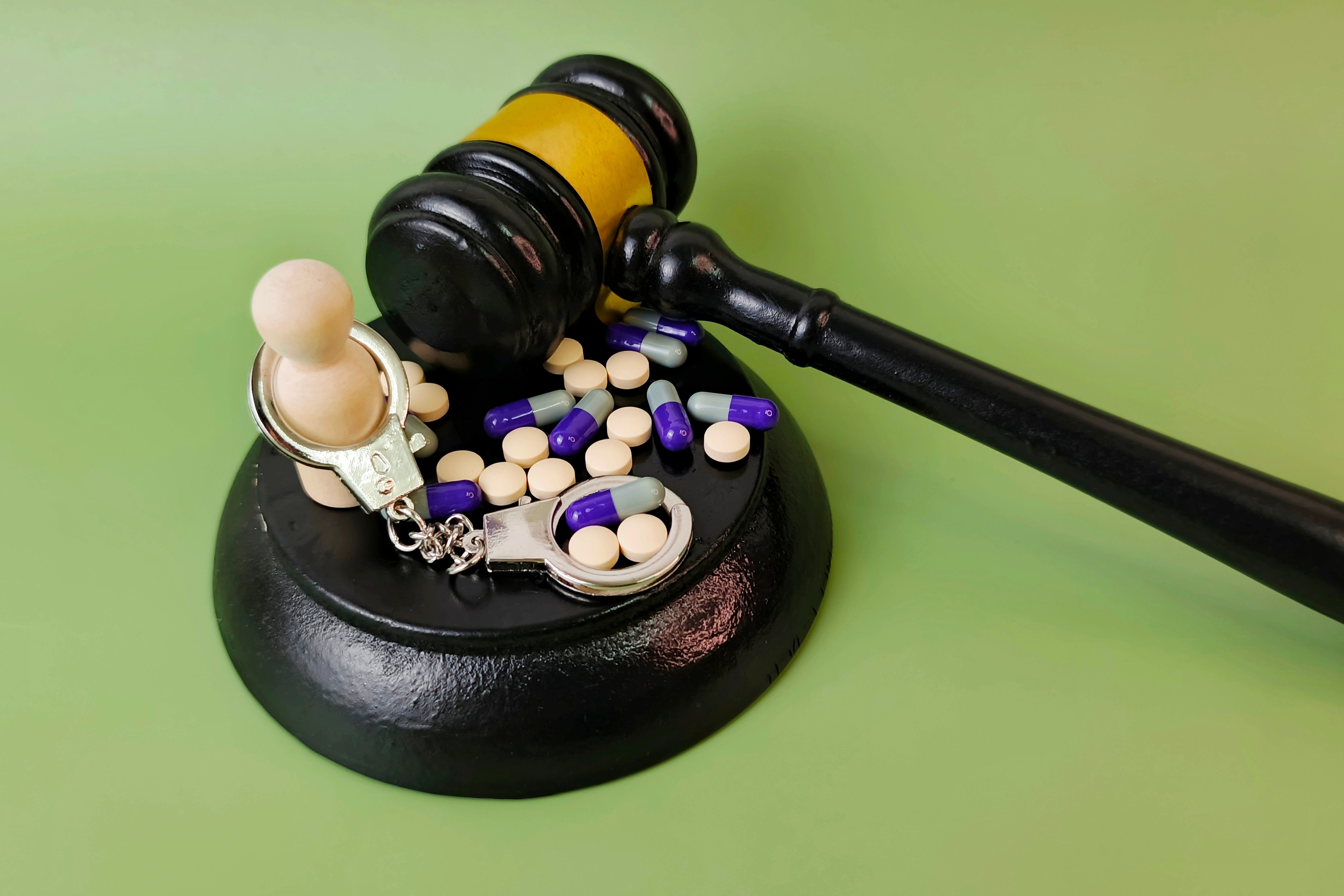 Wooden,Dolls,With,Handcuffs,,Capsules,,Pills,,And,Judge,Gavel,,Drug