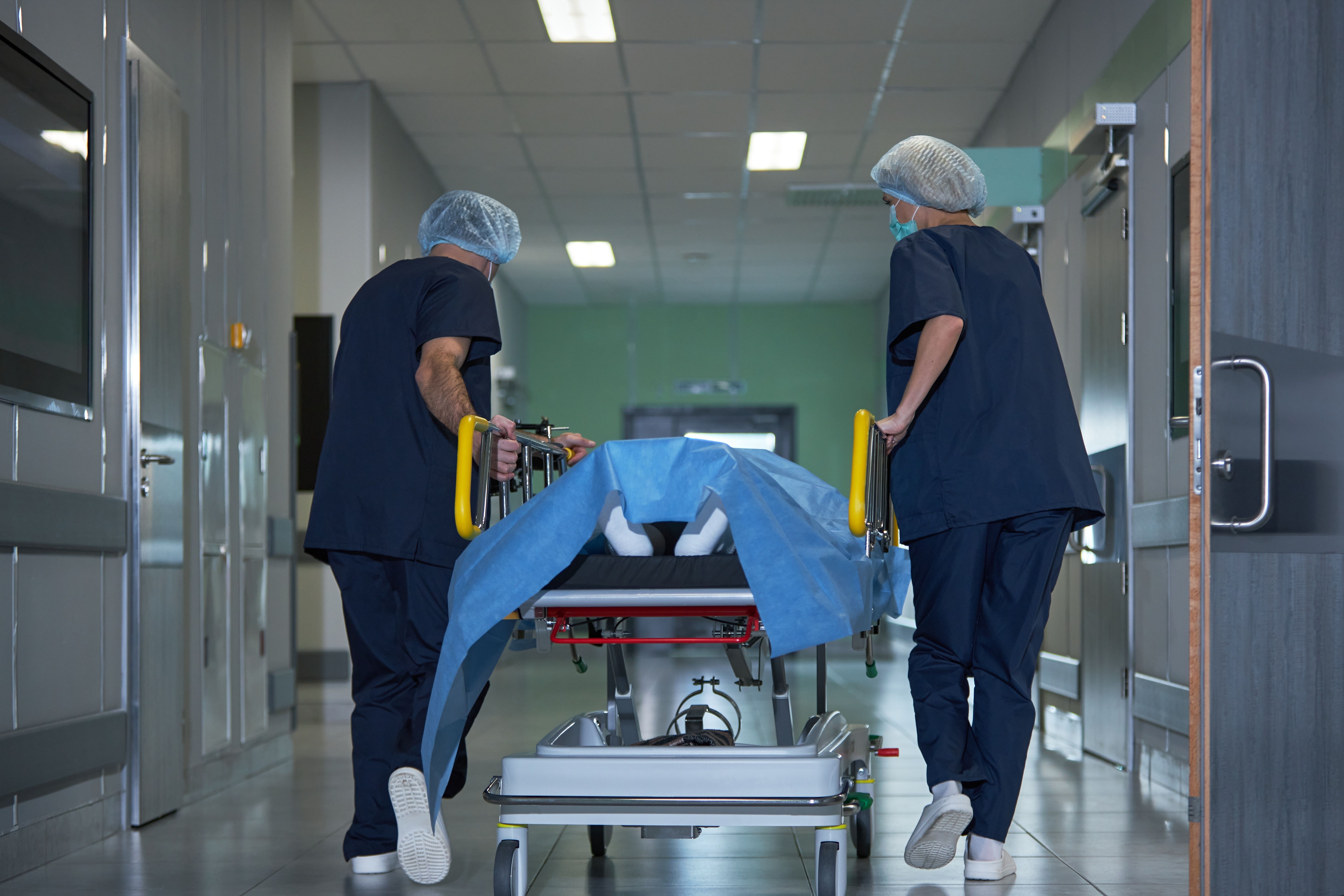 Medical,Team,Transporting,Patient,On,Hospital,Gurney,Through,Corridor,,Preparing