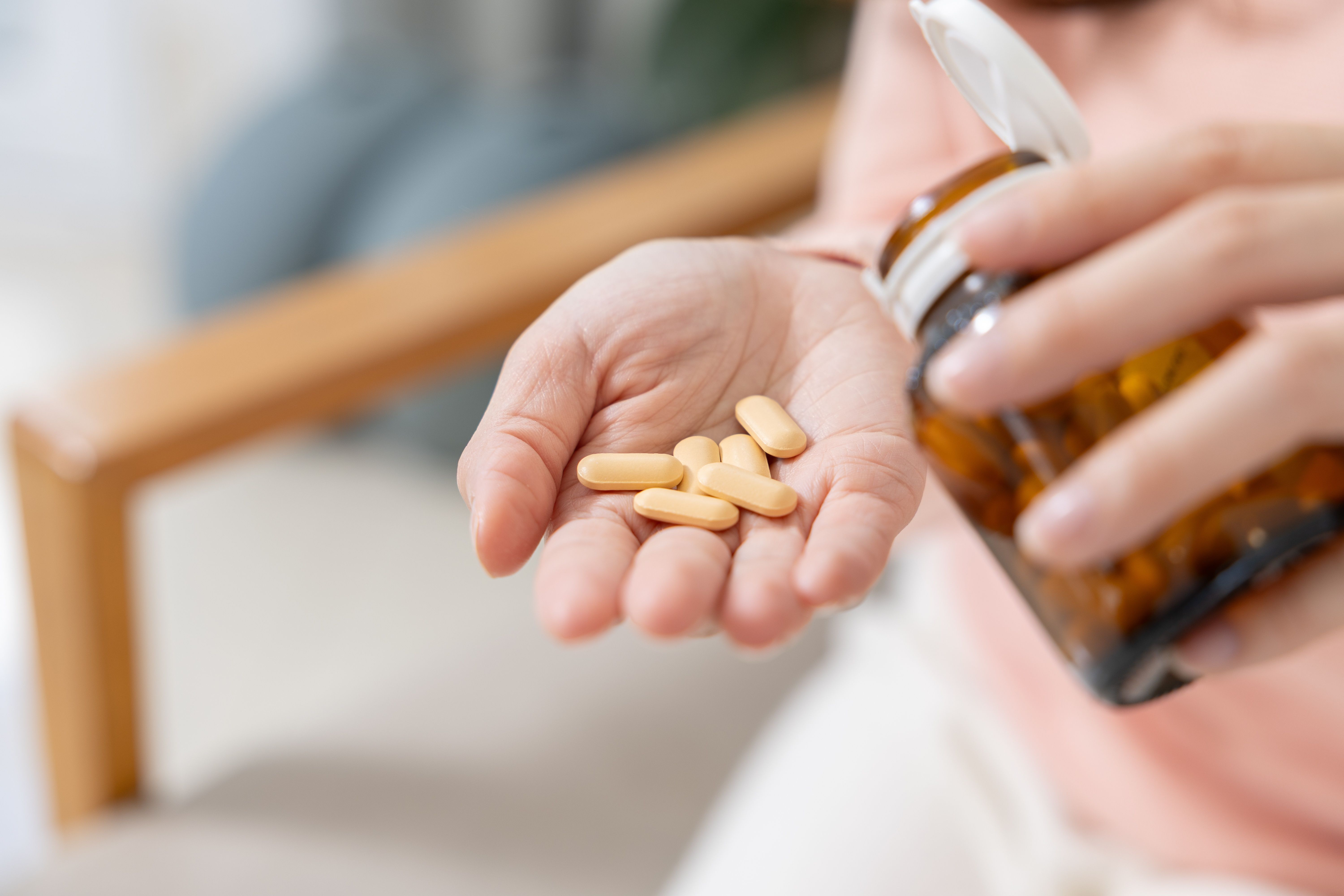 Close,Up,Asian,Female,Hands,Pouring,Yellow,Capsules,From,Brown