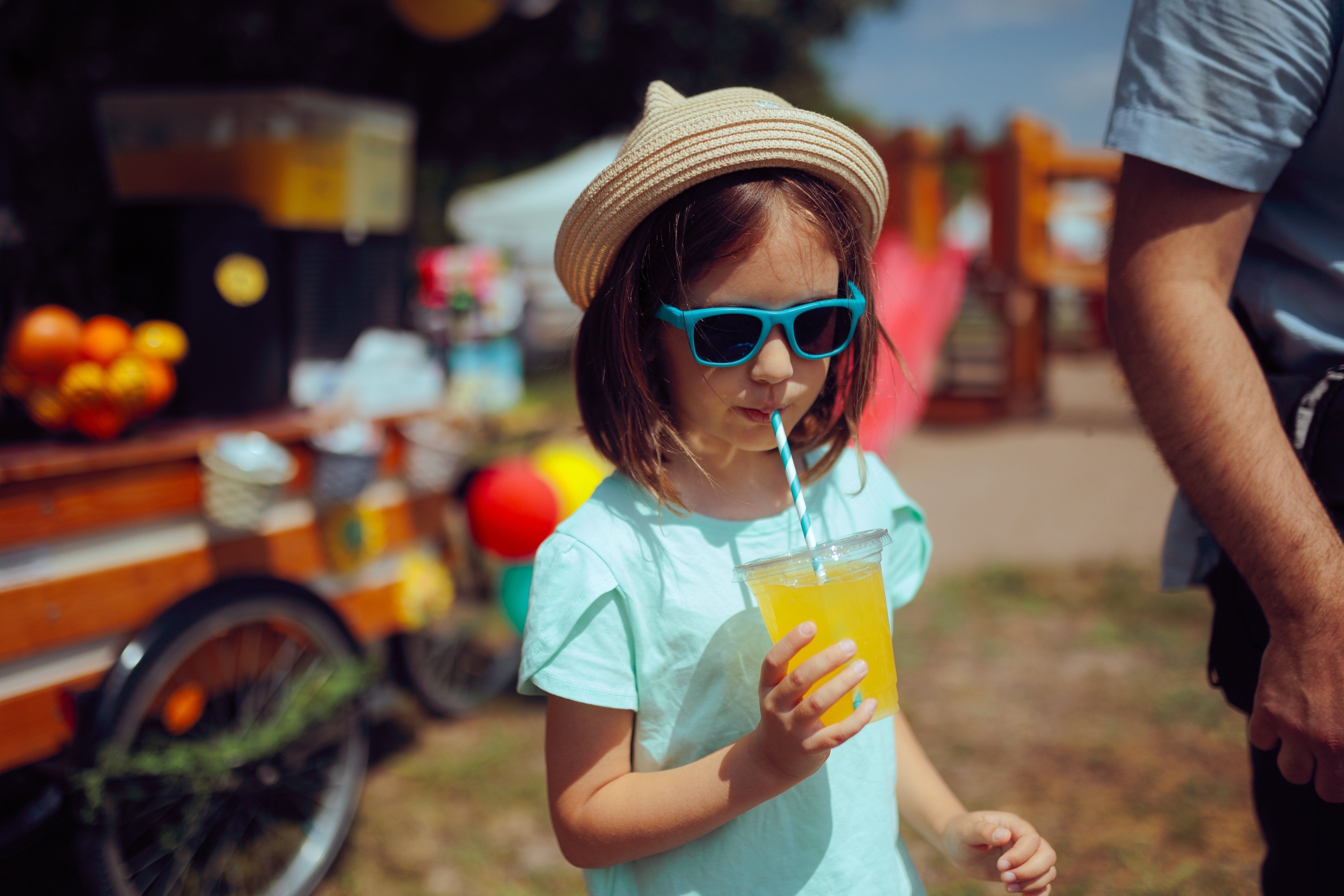 Mała dziewczynka pije lemoniadę na festiwalu dla dzieci.