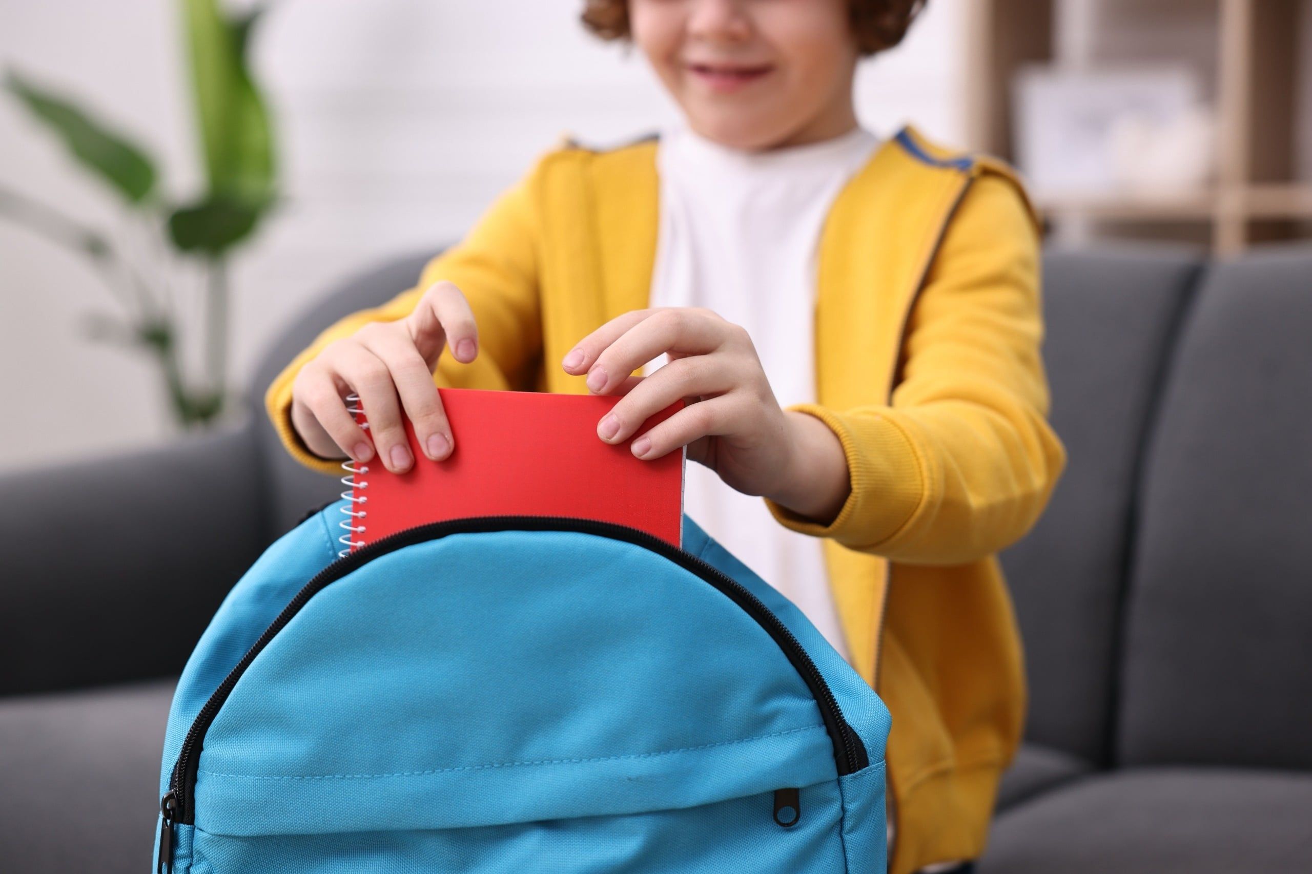 Boy,Packing,His,Backpack,For,School,On,Sofa,At,Home,