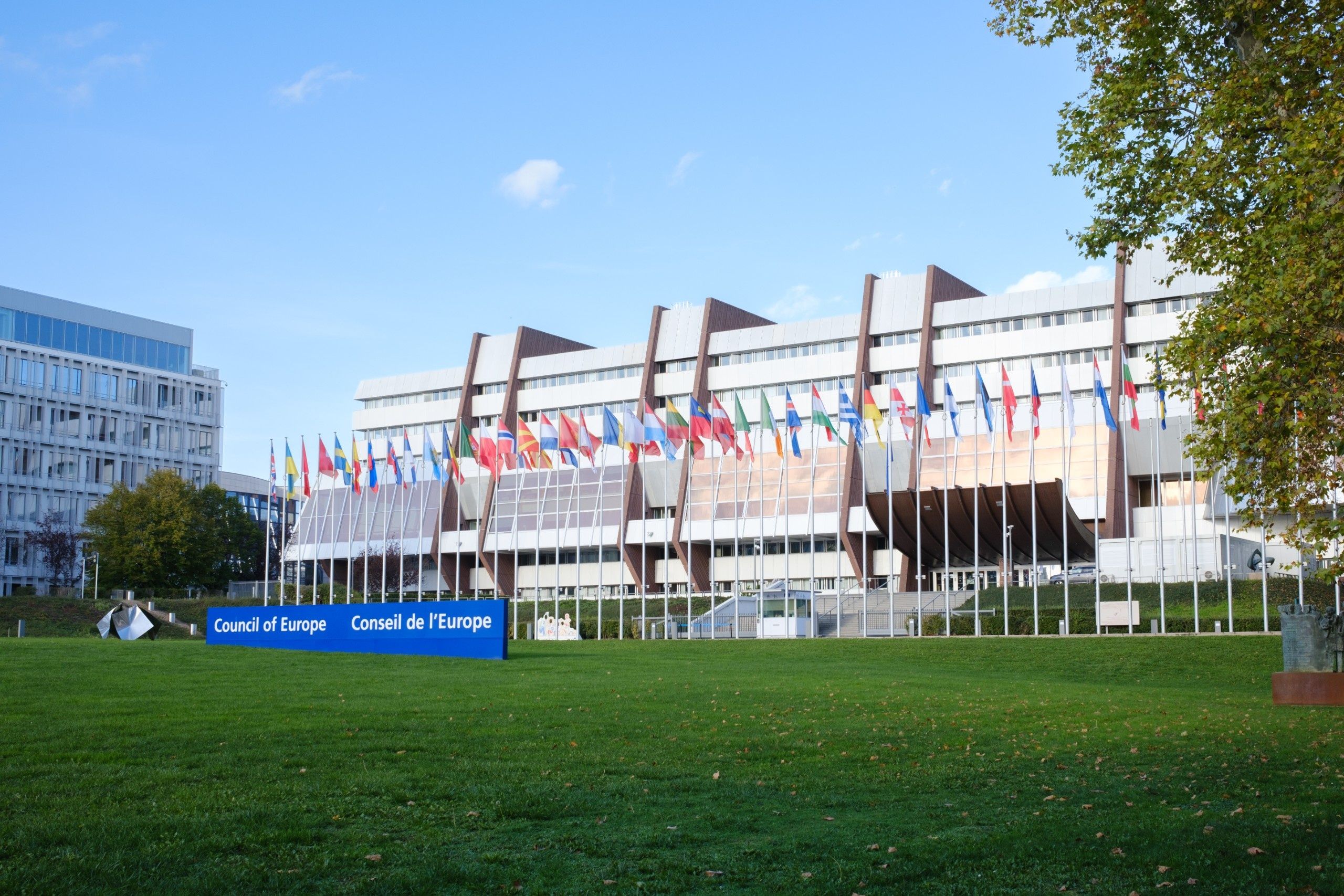 budynek siedziby Rady Europy w Strasburgu z szyldem „Council of Europe" i flagami państw członkowskich