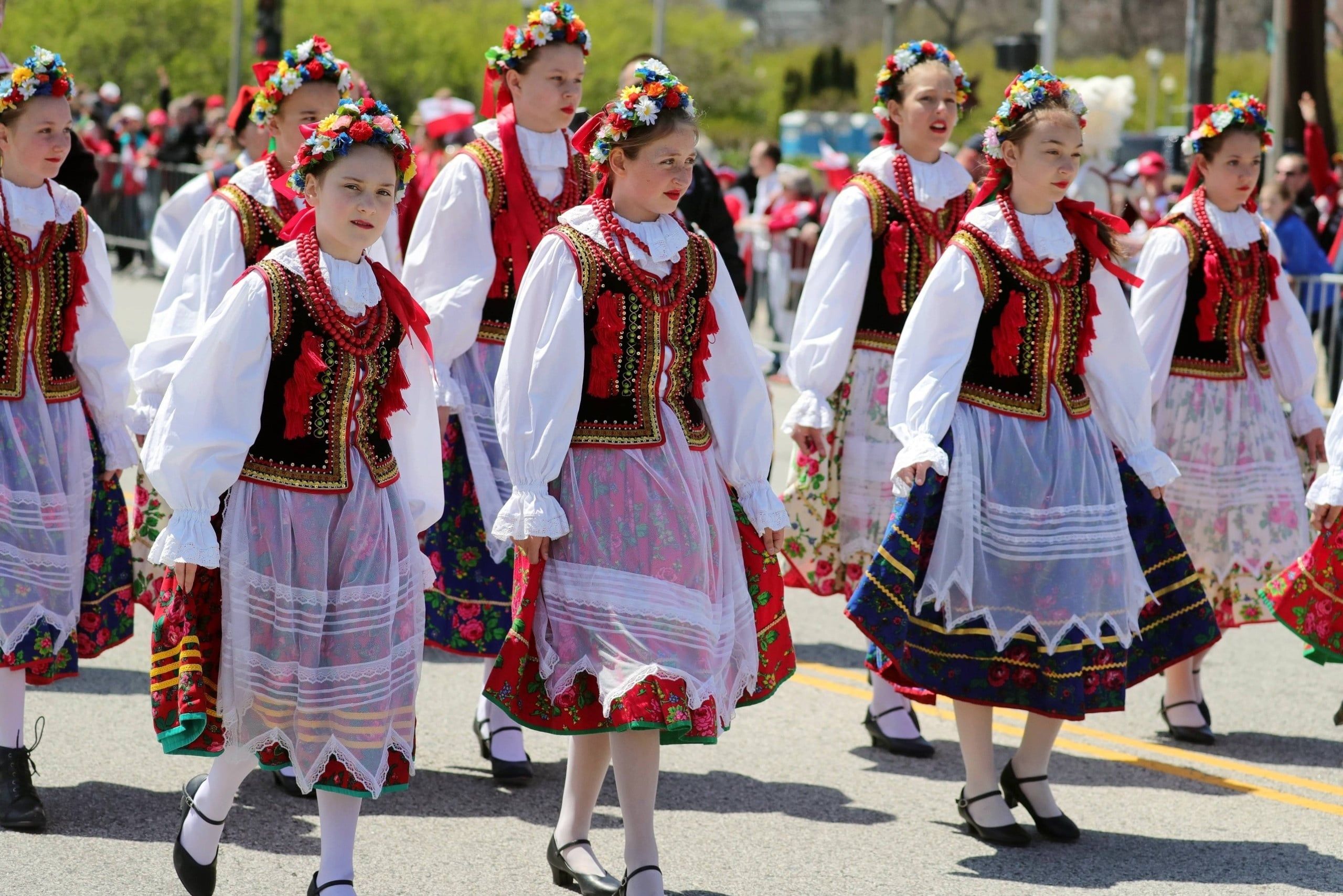 dziewczęta w tradycyjnych polskich strojach ludowych z wiankami kwiatów maszerujące podczas parady Polonii w Chicago
