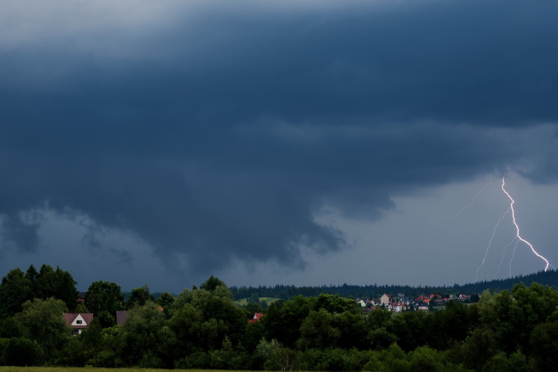 Lightning,Bolt,Striking,Near,Town,Silhouette,And,Forest,During,Summer
