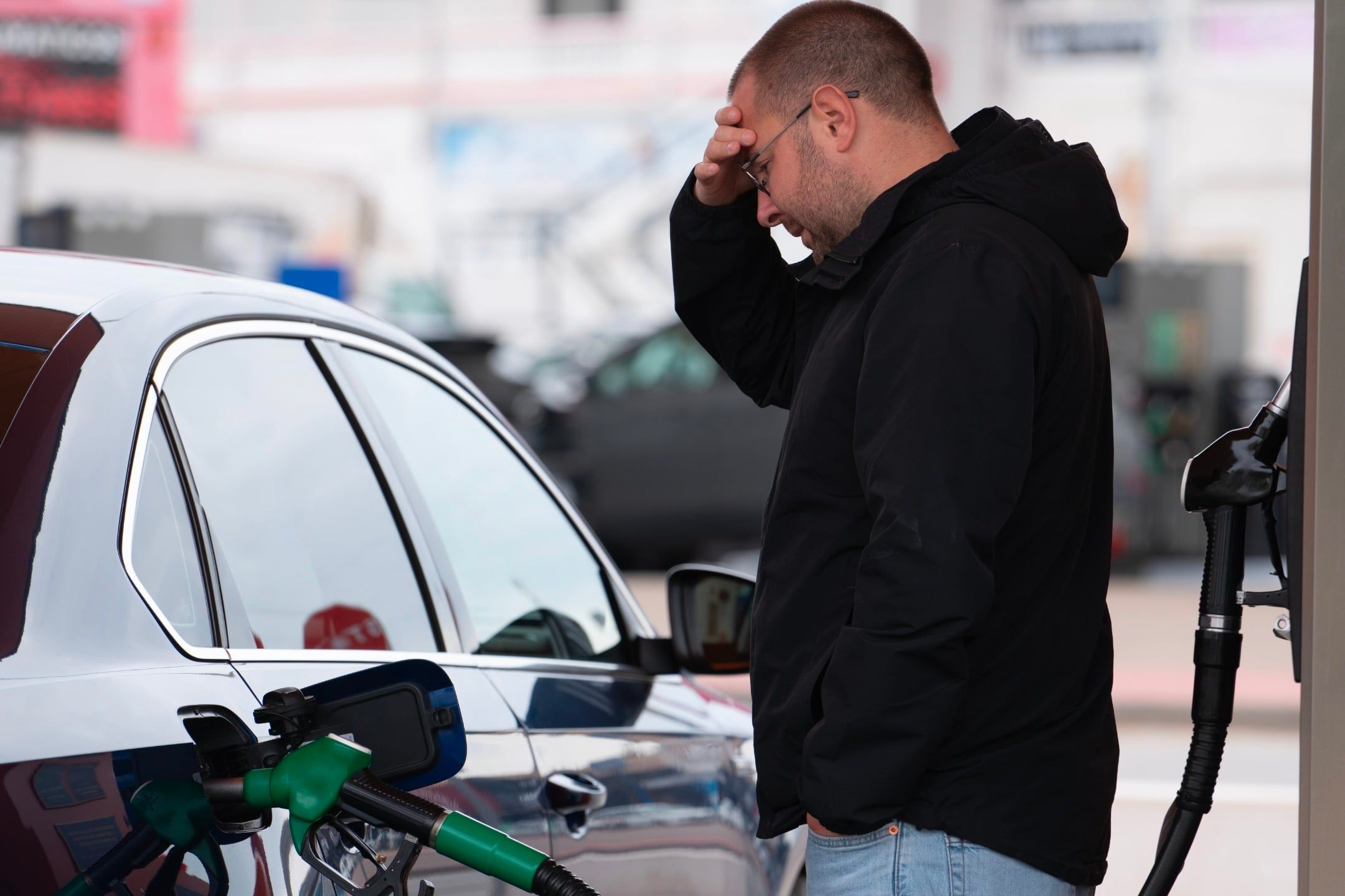 Frustrated,Man,Refueling,Car,At,Gas,Station,Holding,His,Head.