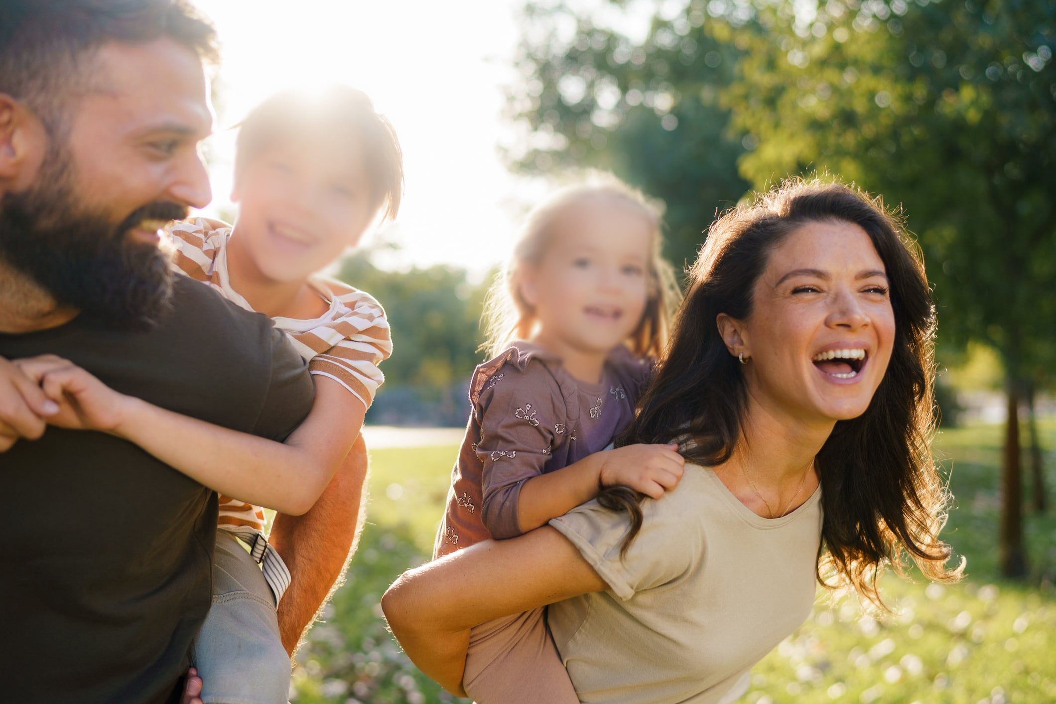 Parents giving children piggyback rides in park