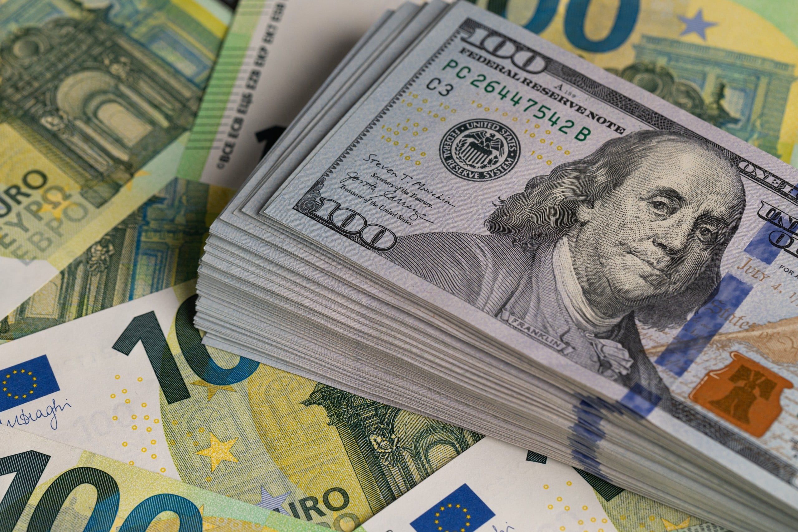 Stack,Of,Us,Dollars,On,Top,Of,Euro,Banknotes,Background