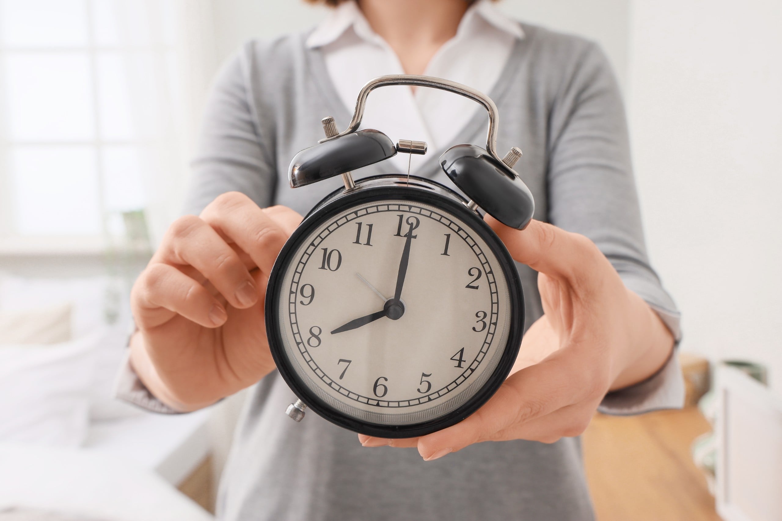 Woman,Setting,Time,On,Alarm,Clock,In,Bedroom,,Closeup.,Daylight