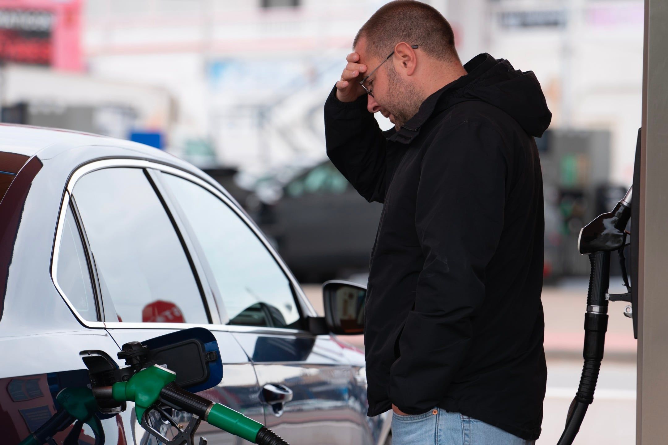 Frustrated,Man,Refueling,Car,At,Gas,Station,Holding,His,Head.