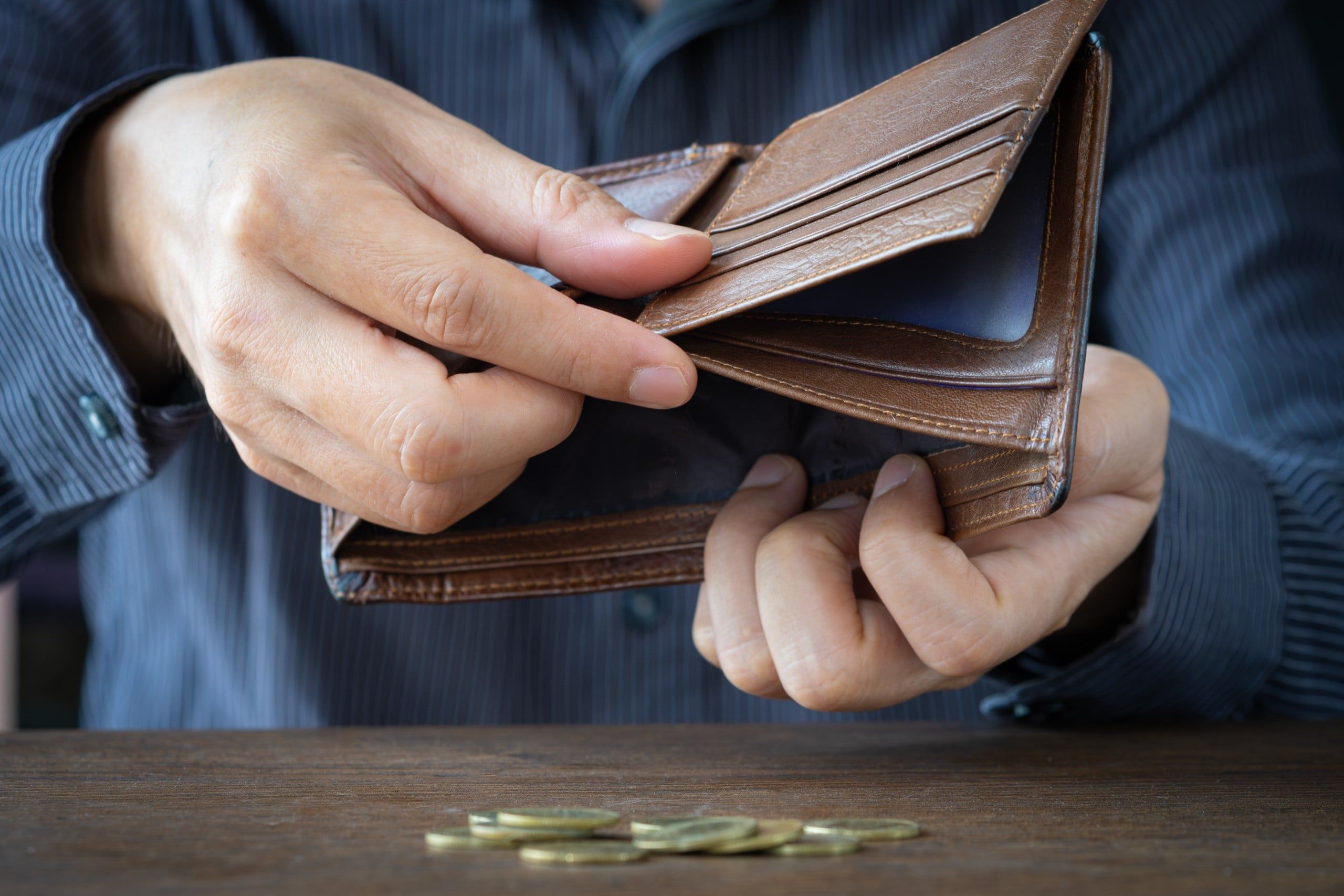 Poor,Man,Hands,Opening,Empty,Leather,Wallet,With,Few,Coins