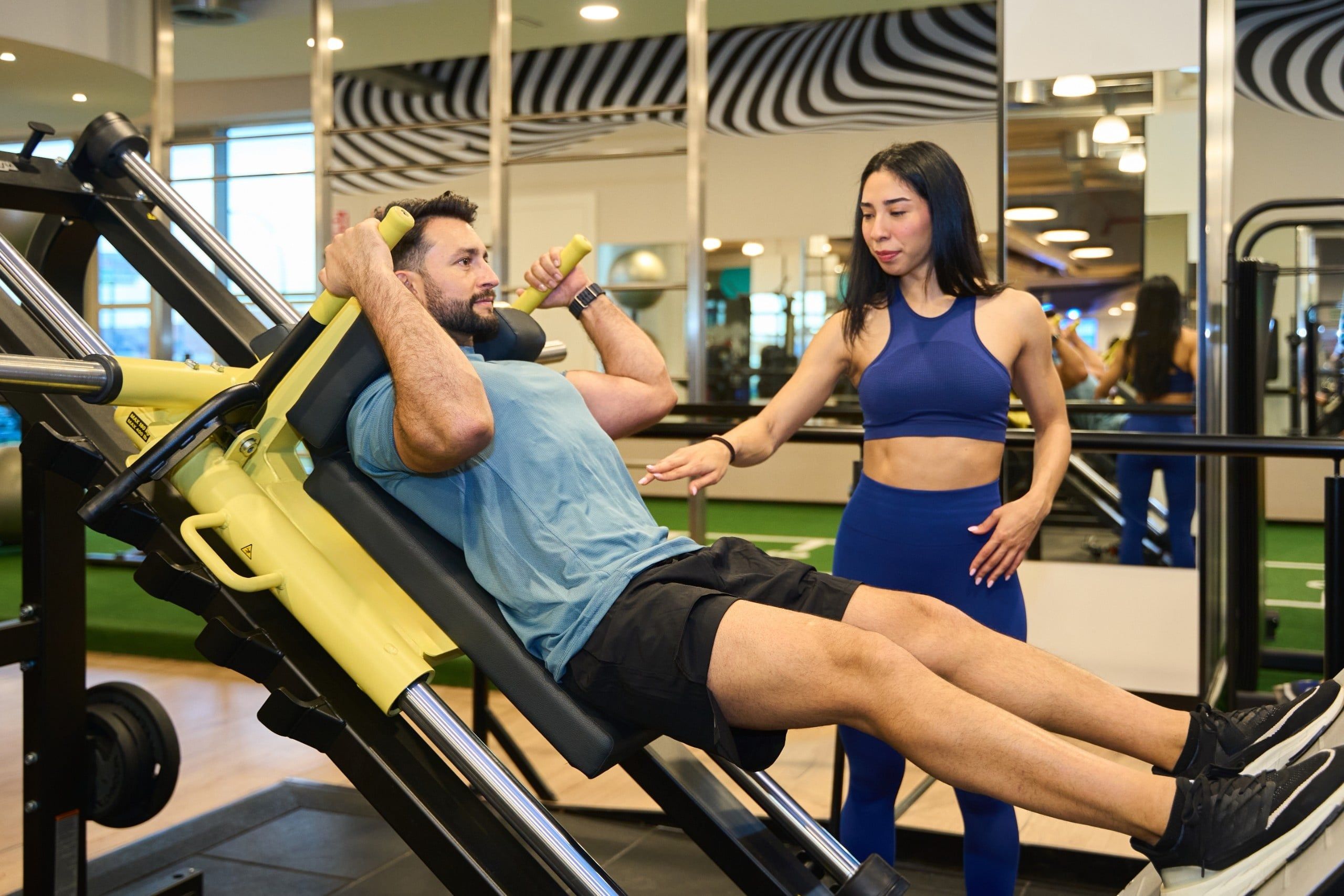Fitness,Trainer,Guiding,A,Client,Through,A,Leg,Press,Workout