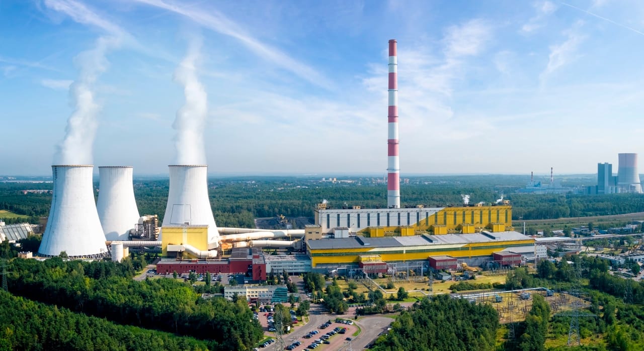 Kominy elektrowni emitujące dym na tle błękitnego nieba, ujęcie z lotu ptaka