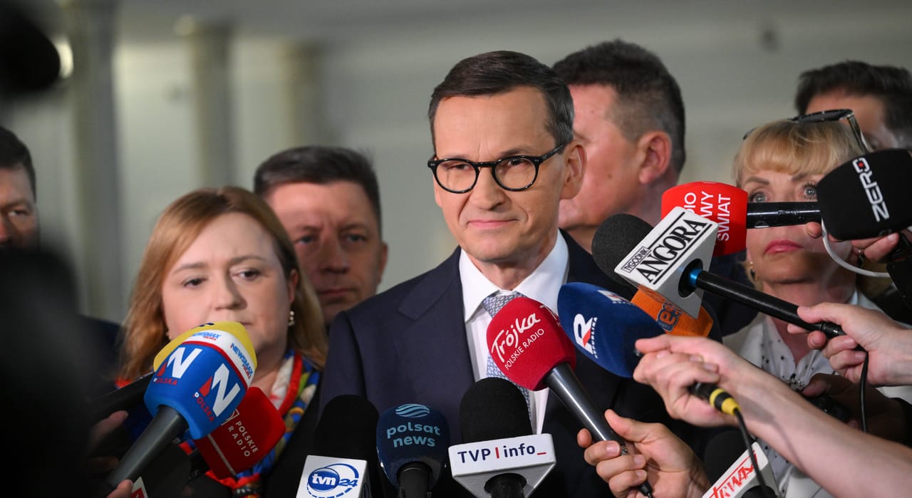 Mateusz Morawiecki odpowiadający na pytania dziennikarzy, w tle mikrofony radiowe