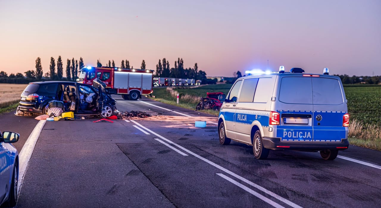 Miejsce wypadku drogowego z pojazdami policji i straży pożarnej o zmierzchu