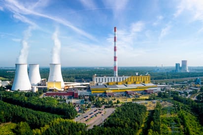 Kominy elektrowni emitujące dym na tle błękitnego nieba, ujęcie z lotu ptaka