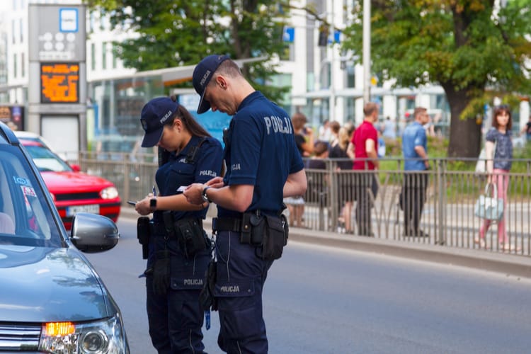 Funkcjonariusze policji wypisująca mandat za wykroczenie drogowe