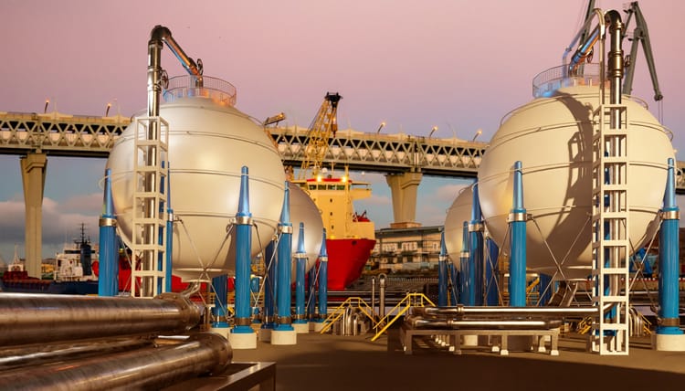 Przemysłowy terminal portowy ze sferycznymi zbiornikami wodoru, rurociągami i statkiem towarowym do transportu energii w pobliżu mostu.