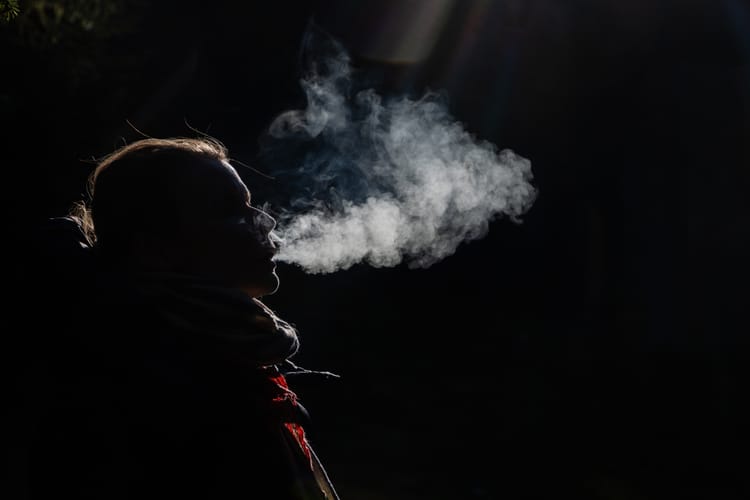 Young,Woman,Smoking,On,A,Dark,Background