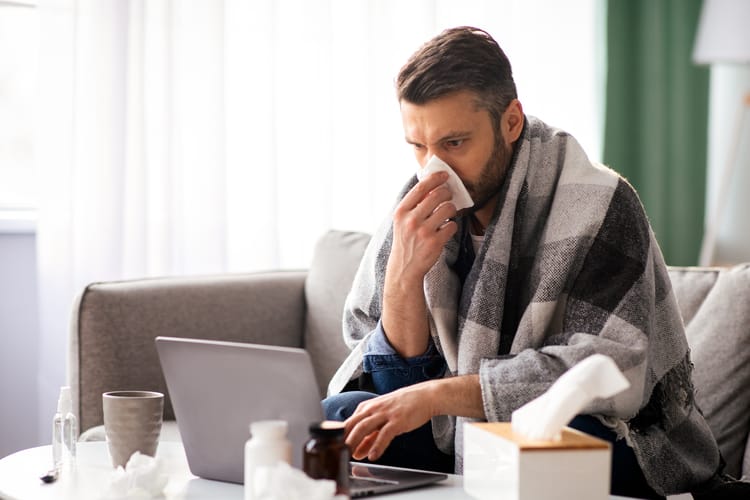 Sick,Man,Sneezing,Nose,While,Working,On,Laptop,At,Home