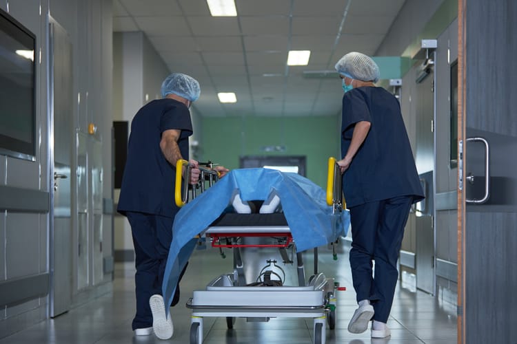 Medical,Team,Transporting,Patient,On,Hospital,Gurney,Through,Corridor,,Preparing